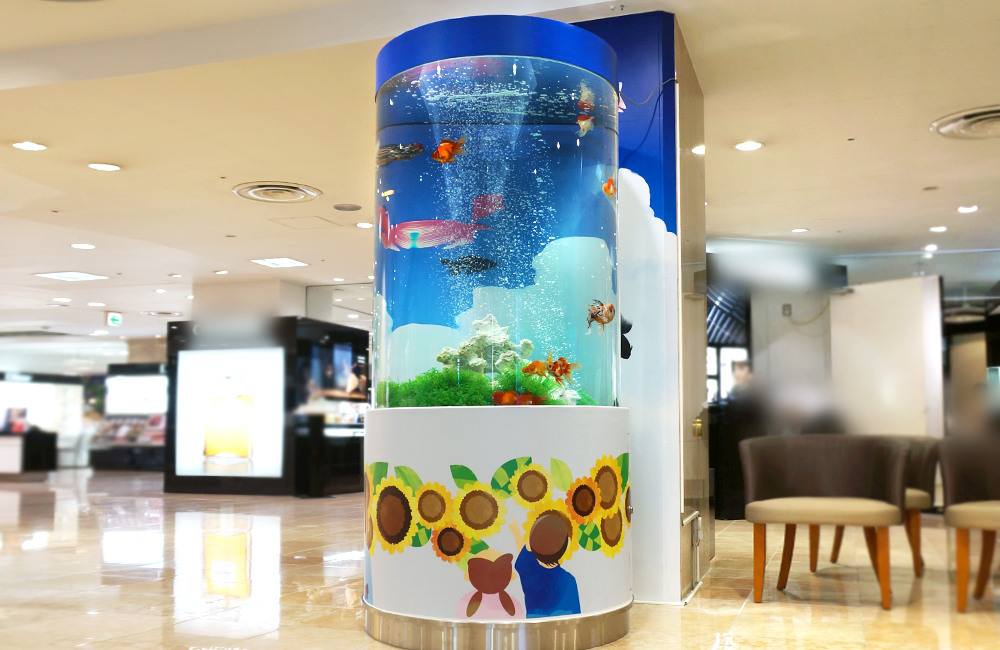 ひまわりのイラストが描かれた円柱型の金魚水槽