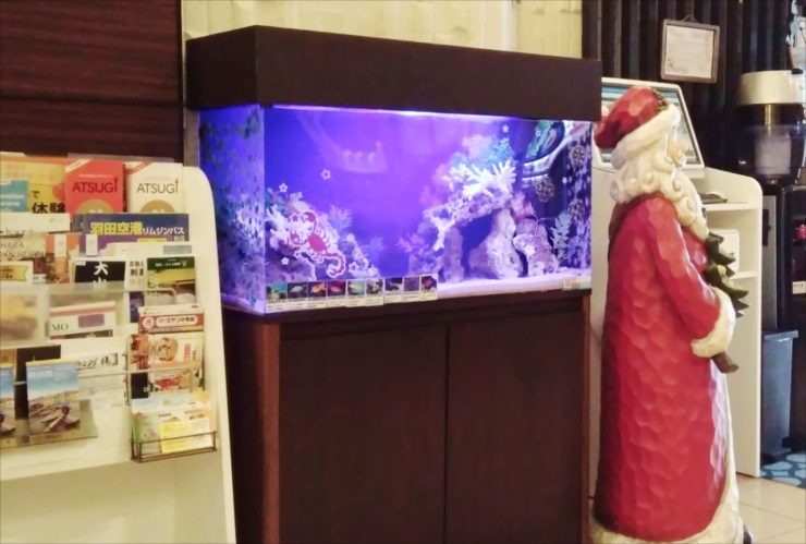 サンタの人形と並んで設置された青い照明の海水魚水槽