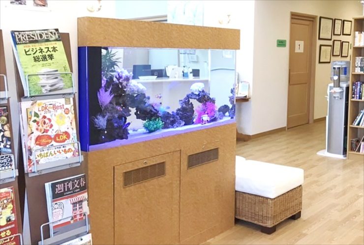 待合室に設置された木目調大型水槽とマガジンラック