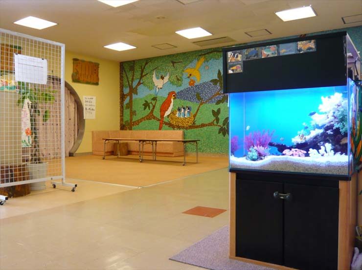 室内に設置された海水魚水槽と鳥の壁画がある待合室