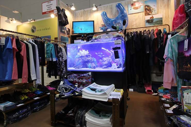 衣類やダイビング用品に囲まれた海水魚水槽の展示風景