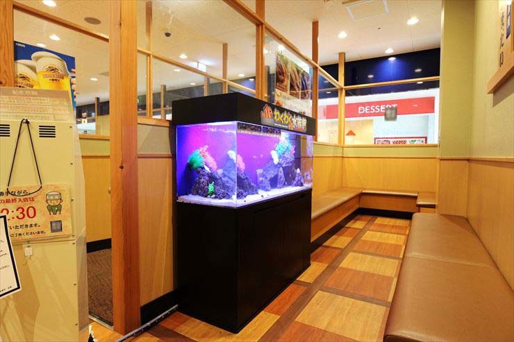飲食店待合室に設置された紫色の照明が光る大型水槽