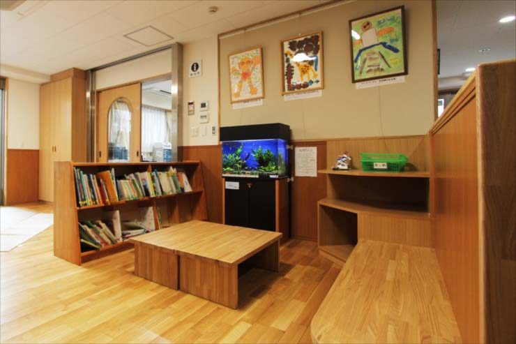 木目調の室内に設置された青い照明の水槽と本棚