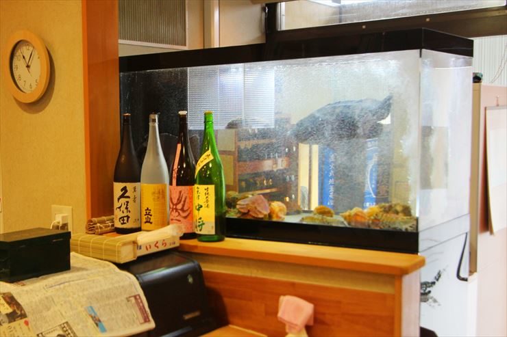 日本酒の瓶が並ぶカウンターに設置された大型の活魚水槽