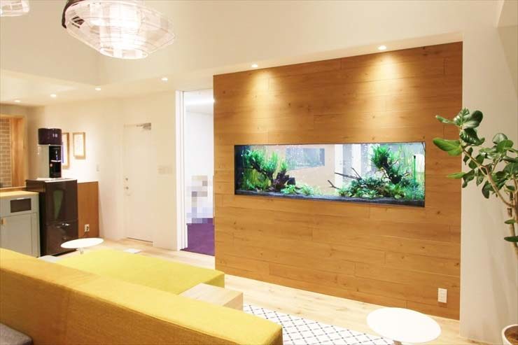 木目調の壁面に埋め込まれた横長の水草水槽と室内風景