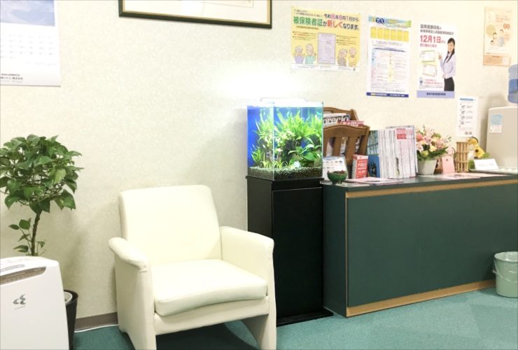 待合室の白い椅子と水草が茂る小型水槽の設置風景