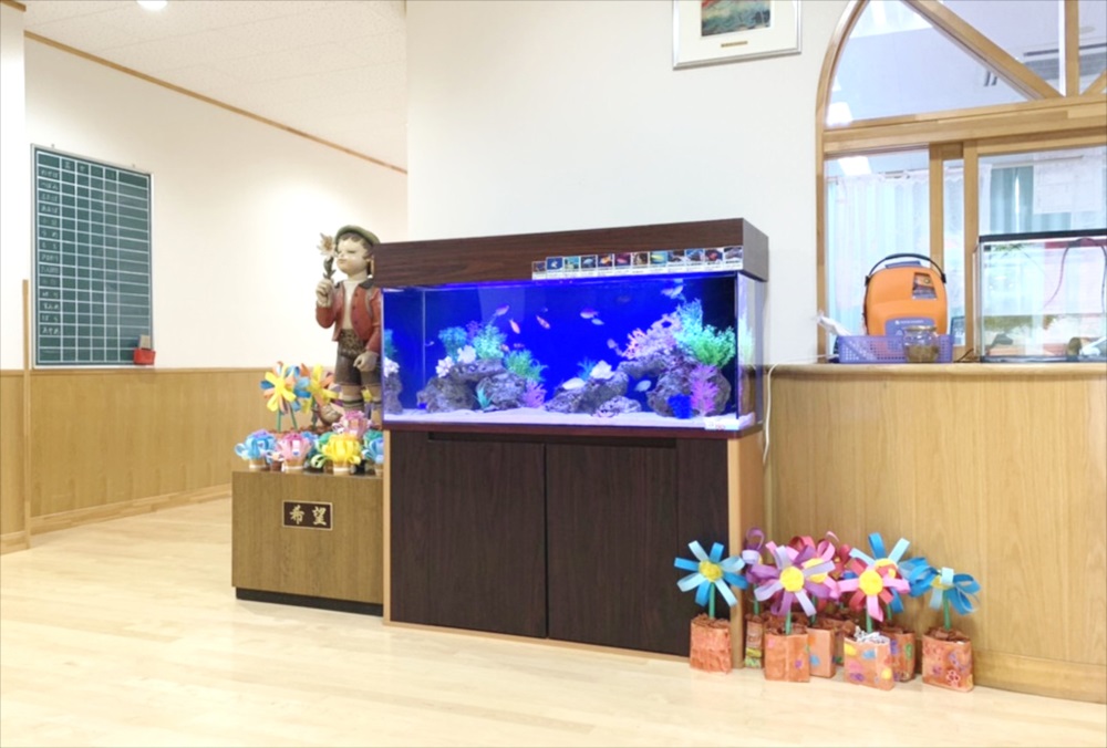 施設内に設置された熱帯魚水槽と造花の装飾品