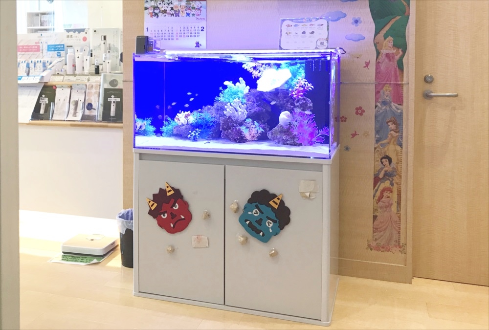 鬼の装飾がある水槽台と青い照明の海水魚水槽