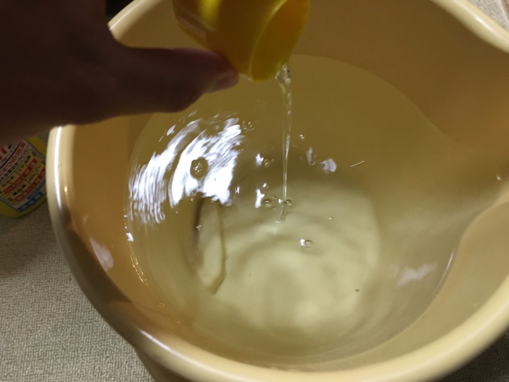 バケツに溜めた水へカルキ抜きを投入する手元画像