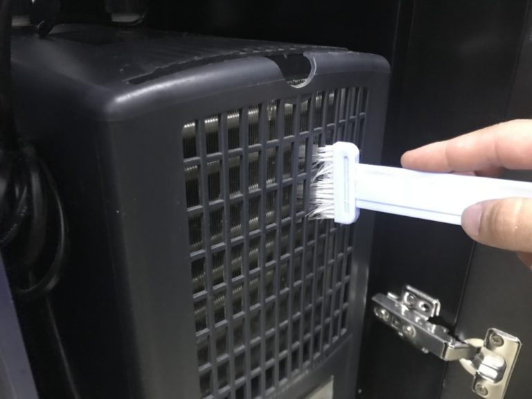 水槽用クーラーの吸気口をブラシで掃除する手元