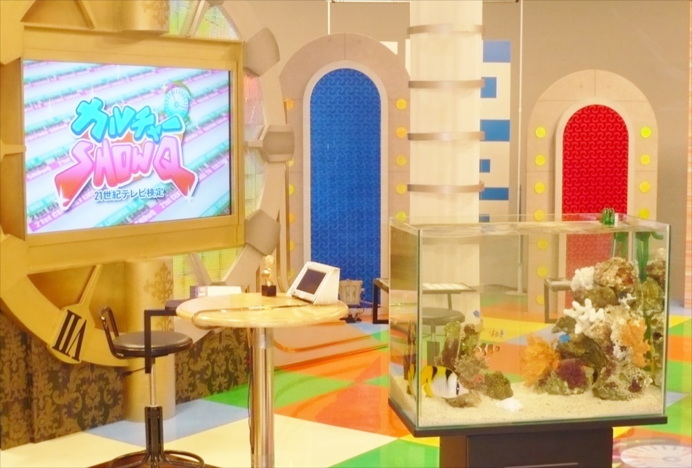 テレビ番組セットに設置された海水魚水槽とモニターの風景