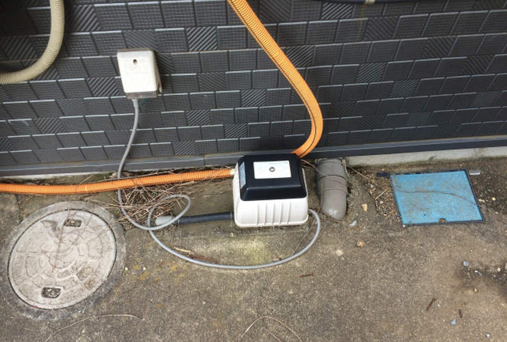 屋外の壁際に設置された浄化槽用ブロワーと配線配管