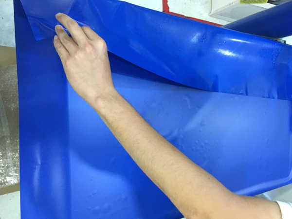 水槽の背面に青いバックスクリーンを貼り付ける手元