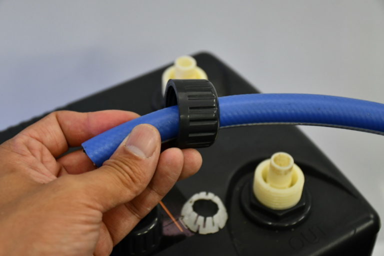 水槽用クーラーの接続口に青いホースを通す手元