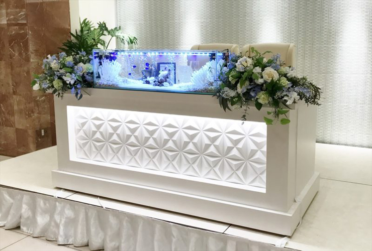 花に囲まれた水槽が置かれた結婚式場の高砂席