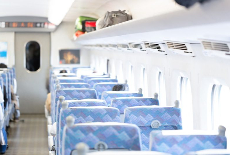 青い座席が並ぶ新幹線の車内と荷棚の荷物