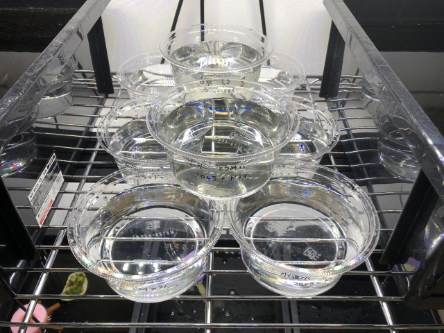 スチールラックに並ぶ水が入った複数の透明プラスチック容器
