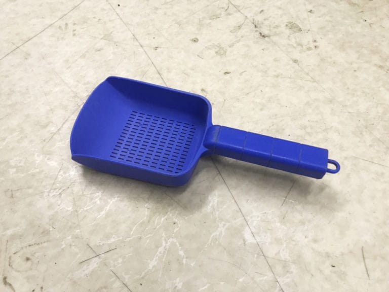 床に置かれた青いプラスチック製の水槽掃除用スコップ