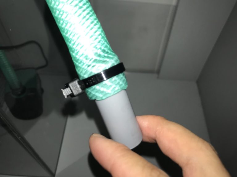 結束バンドで固定された緑のホースとグレーの塩ビパイプ