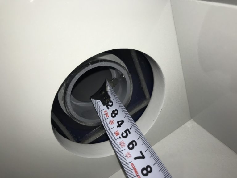 メジャーで水槽台の配管穴の直径を計測する様子