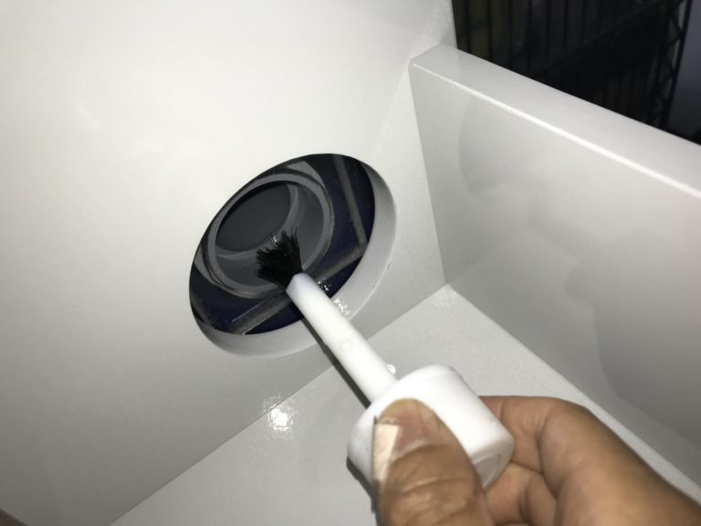 白い水槽台の穴にハケで塗料を塗る手元のアップ