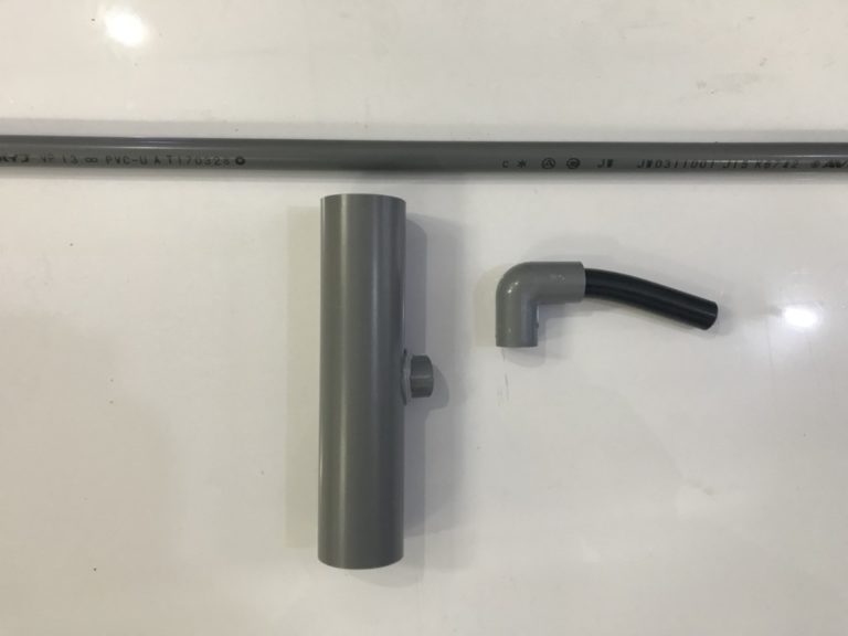 グレーの塩ビパイプとエルボ継手および黒いホースの部品