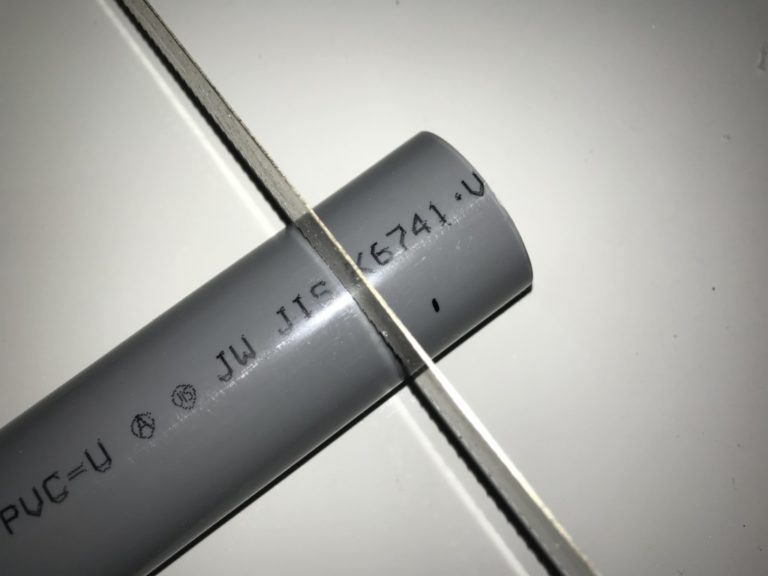 のこぎりの刃で切断されるグレーの塩ビパイプ