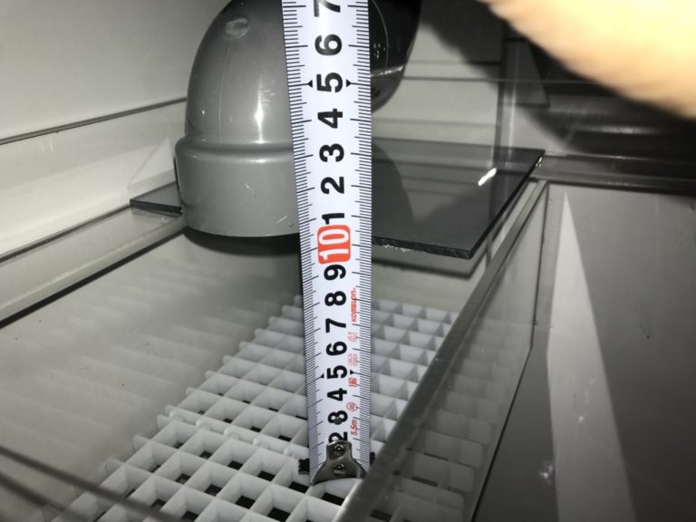 メジャーで水槽内の配管の高さを測る様子