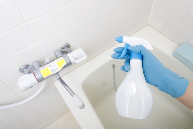 ゴム手袋をはめた手で持つ浴室用洗剤スプレーボトル