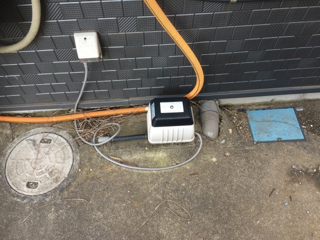 屋外の壁際に設置された浄化槽用ブロワーポンプ