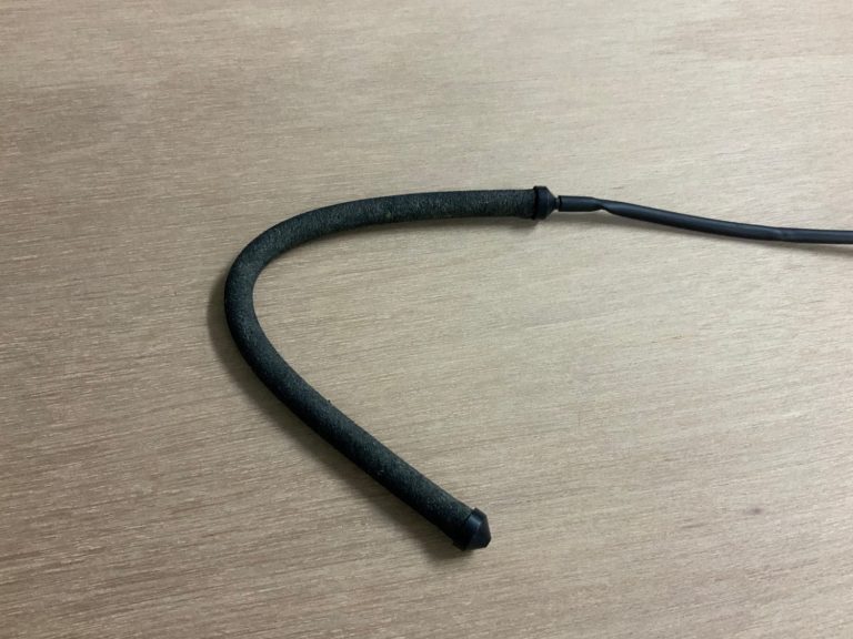 木目調の板の上に置かれた黒いエアーカーテン用ホース