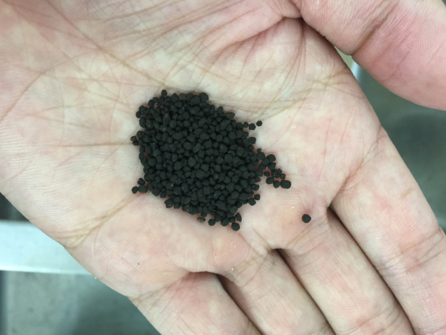 手のひらに乗せたアクアリウム用の黒いソイルの粒