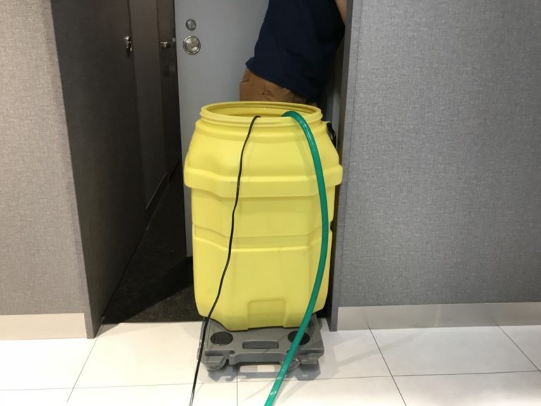 台車に載せた黄色い大型貯水タンクと緑色のホース