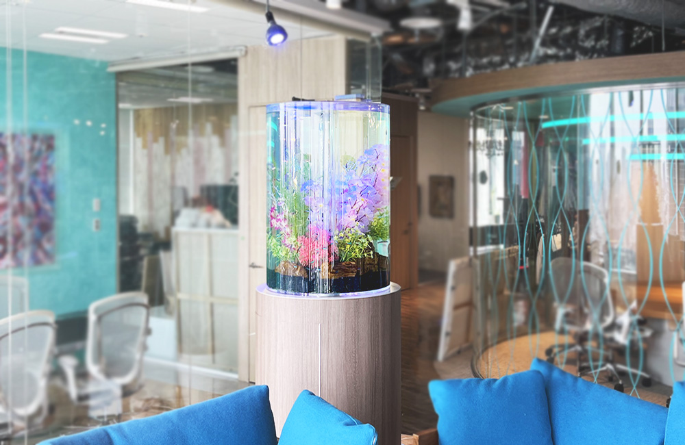 オフィスに設置された円柱水槽と青いソファの風景