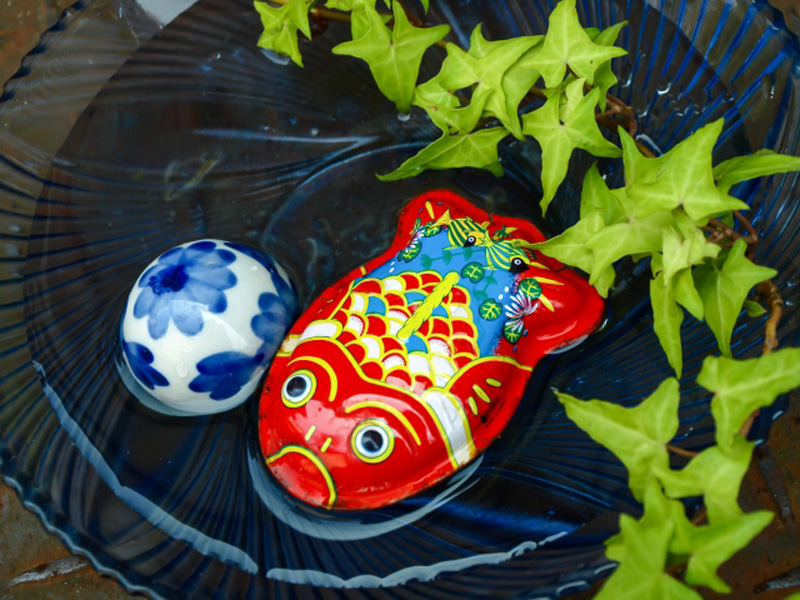 水に浮かぶ金魚の玩具と浮き玉とアイビーの葉