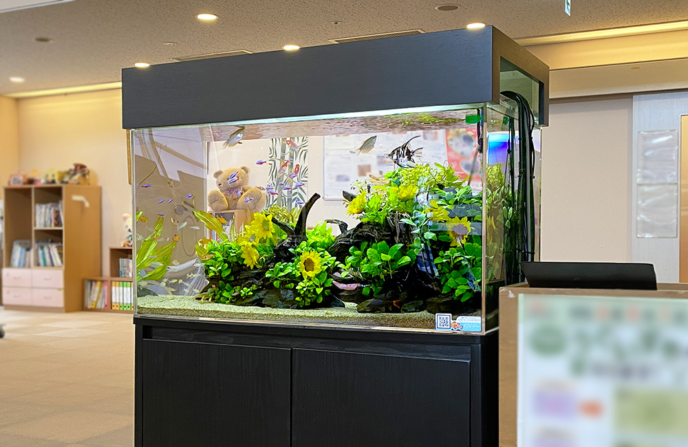 ひまわりの造花と水草で飾られた大型の熱帯魚水槽