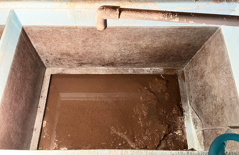 茶色の泥水が溜まった四角い水槽と配管の俯瞰