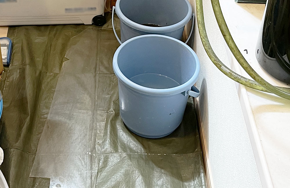 防水シートの上に置かれた水が入った2つの青いバケツ