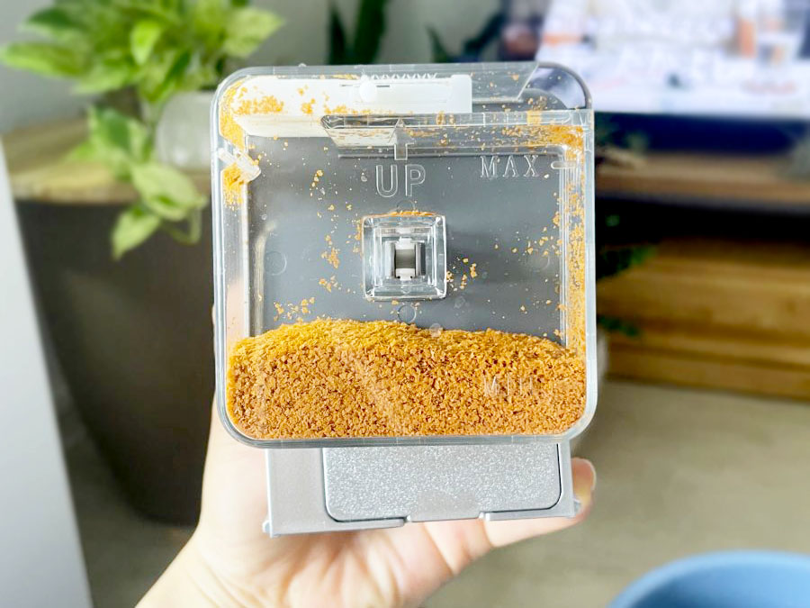 茶色の顆粒状の餌が入った自動給餌器の透明な容器