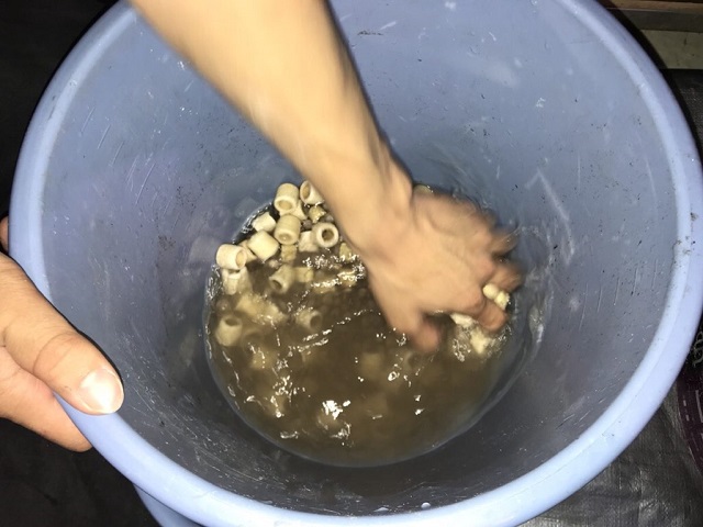 バケツの中でリングろ材を水洗いする手元の写真