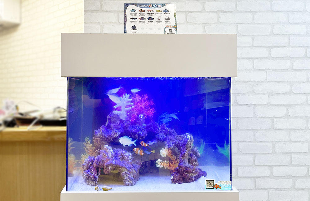 青い照明の海水魚水槽と白いレンガ調の壁面背景