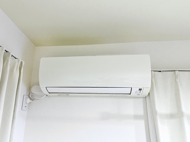 白い壁に設置された家庭用エアコンとカーテン
