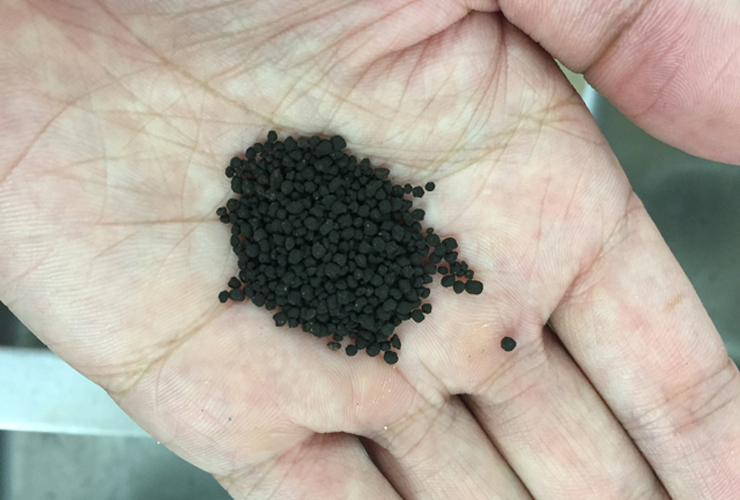 手のひらに乗せた黒色の水槽用ソイルの粒