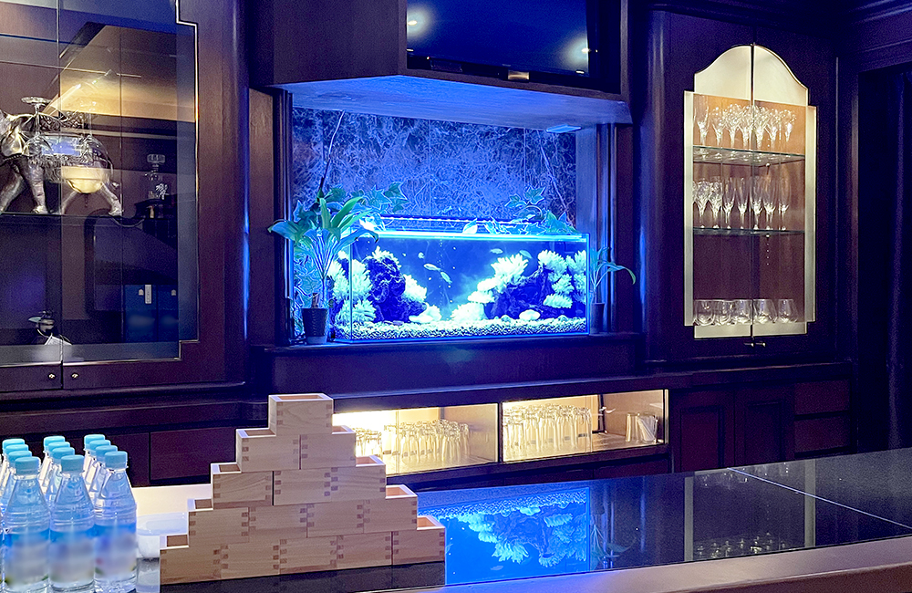 青い照明の熱帯魚水槽があるバーカウンターの風景