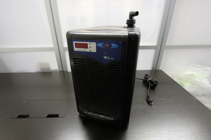 黒いデスクに置かれた水槽用クーラー本体と電源コード