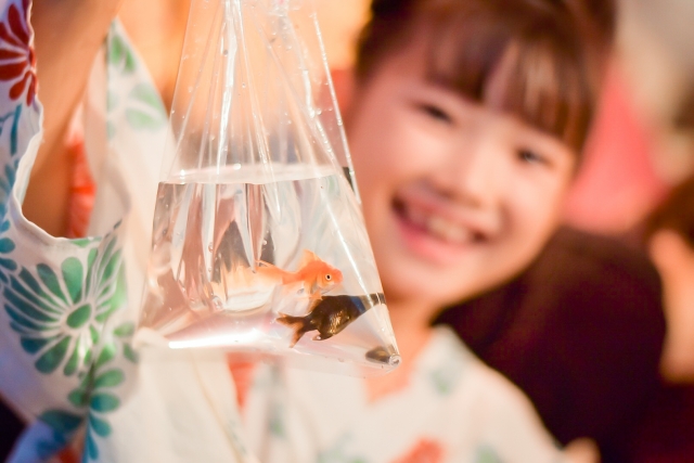 金魚の入った袋を持つ浴衣姿の笑顔の女の子