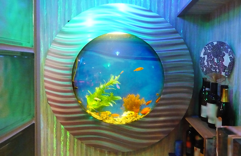 円形フレームに囲まれた水草と小型魚が泳ぐ埋め込み水槽