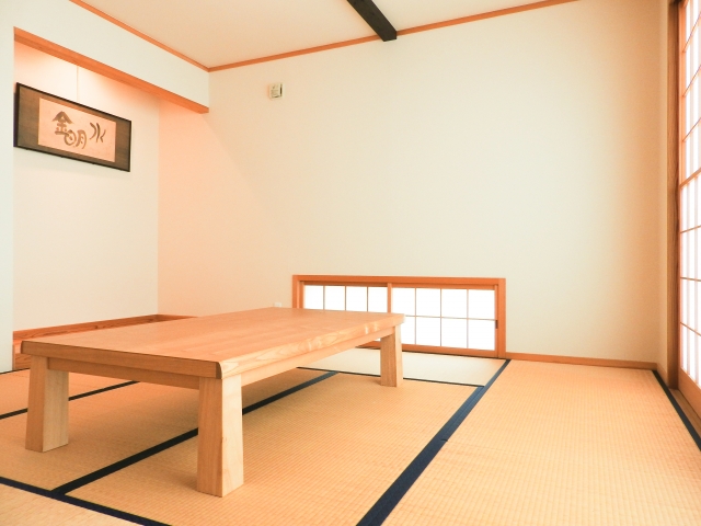 畳敷きの和室に置かれた木製の座卓と掛け軸のある風景