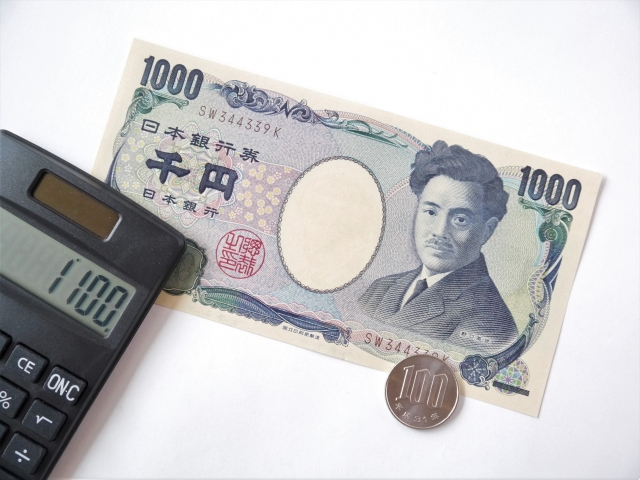 千円札と百円硬貨と黒い電卓の並び
