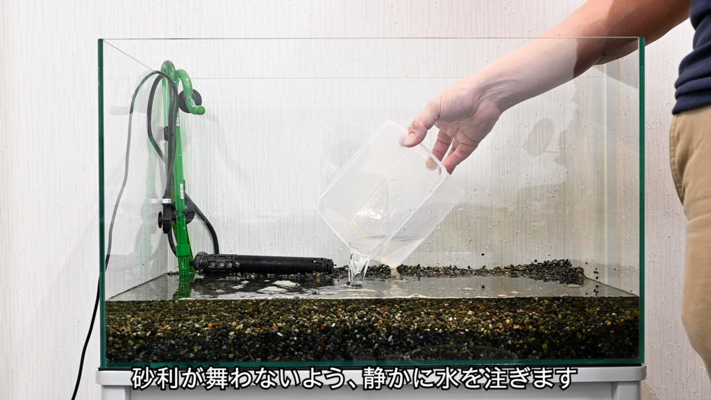 砂利が舞わないよう静かに水を注ぐ水槽の設置風景